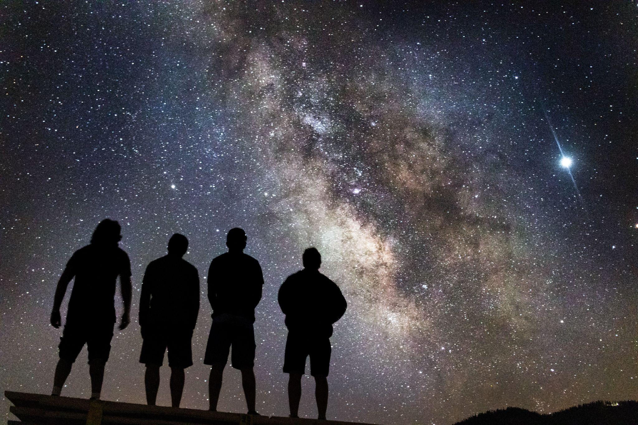 Four people looking at starry night sky 