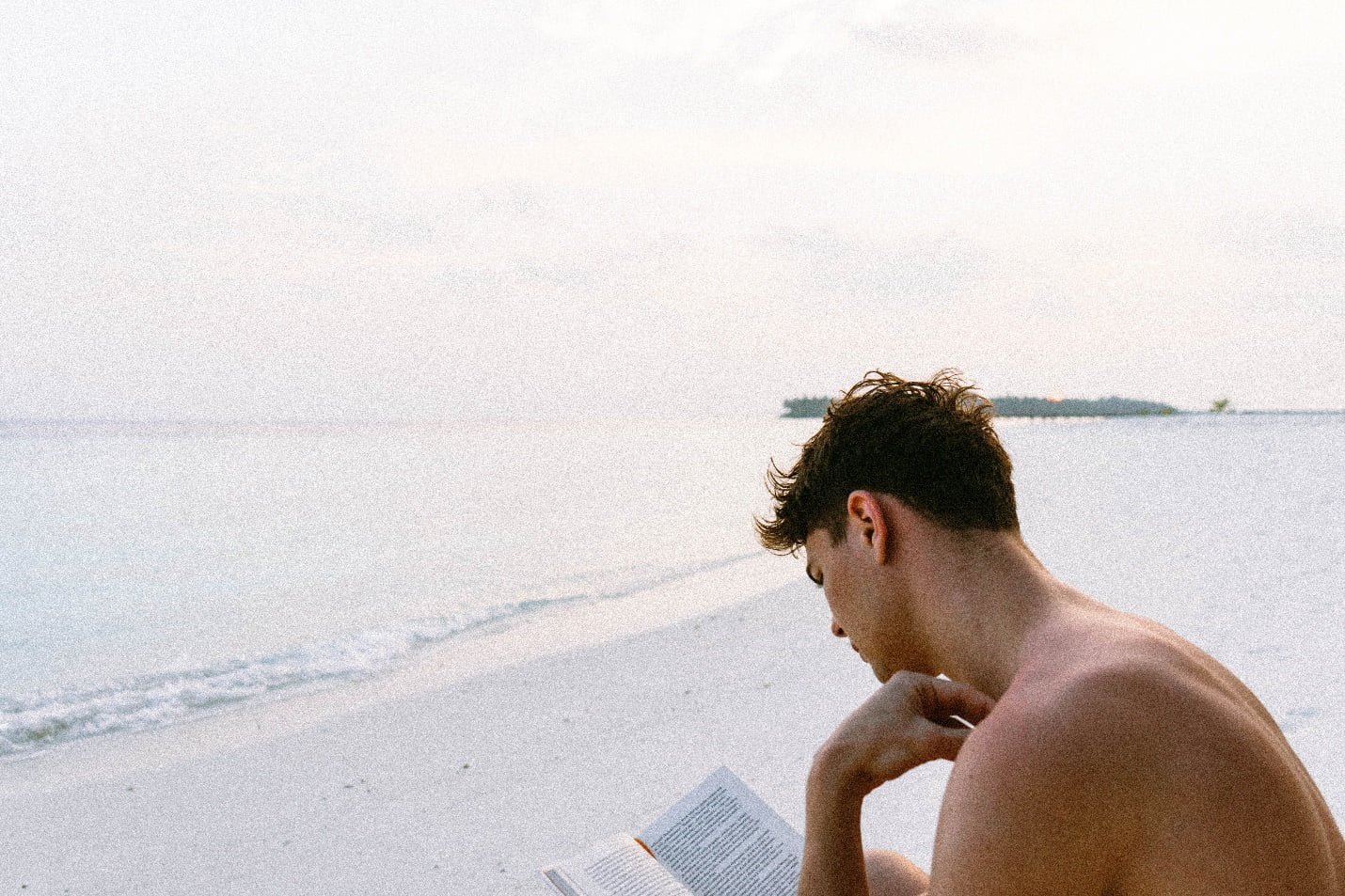 A person reading a book on a beach

Description automatically generated with medium confidence