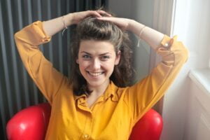 Woman in yellow shirt with her hand on her head